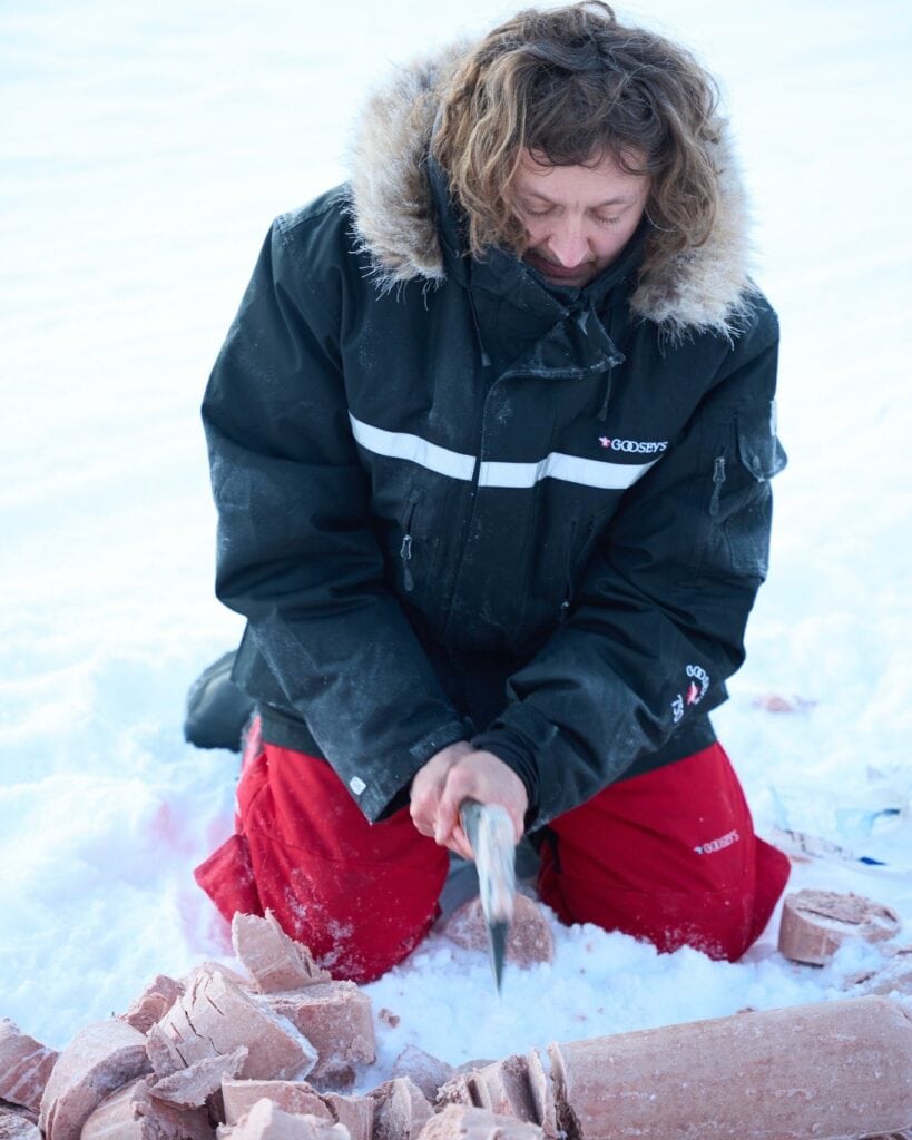 Frozen meat being chopped in the snow for dog food